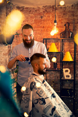 Good looking man visiting barber shop. The barber cuts his hair and trims his beard.