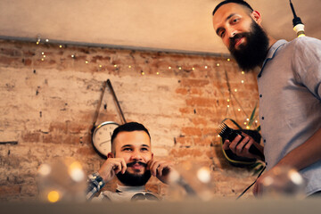 Good looking man visiting barber shop. The barber cuts his hair and trims his beard.