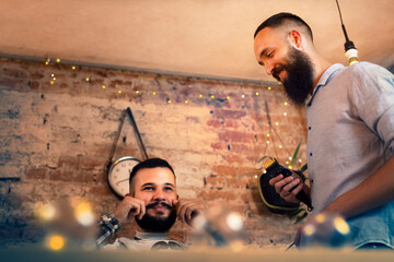 Good looking man visiting barber shop. The barber cuts his hair and trims his beard.