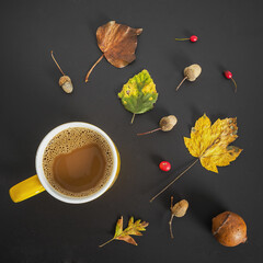 Fototapeta na wymiar Cup of coffee surrounded by autumn leaves, holly, and acorns