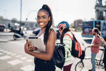 Smiling black female student using tablet outside