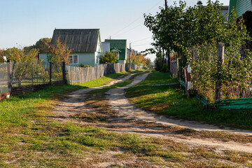 Street of the dacha village. Small houses, dilapidated fences and green grass. Sunny morning....