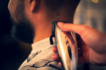 Good looking man visiting barber shop. The barber cuts his hair and trims his beard.