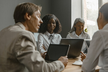 Fun business meeting of the office staff. Colleagues sit at a desk with laptops. High quality photo.