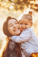 The daughter embracing her mother in the park spending a weekend on a walk in autumn park....