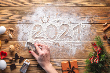 The numbers 2021 are written on flour, which is scattered on a wooden table. Concept of the New year and the cooking of holiday cookies