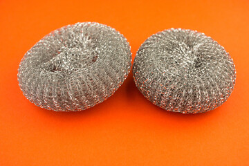 Close-up new metal sponges for washing pans on a bright orange background.Kitchen utensils for washing dishes.Selective focus.