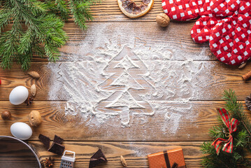 The Christmas tree is drawn on flour, which is scattered on a wooden table. Concept of New Year's mood and preparation of festive pastries