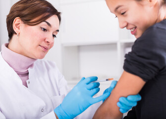 Obraz premium Doctor in white medical gown does compulsory vaccination to girl in hospital