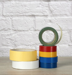 stack of colorful insulating tape on white brick wall background