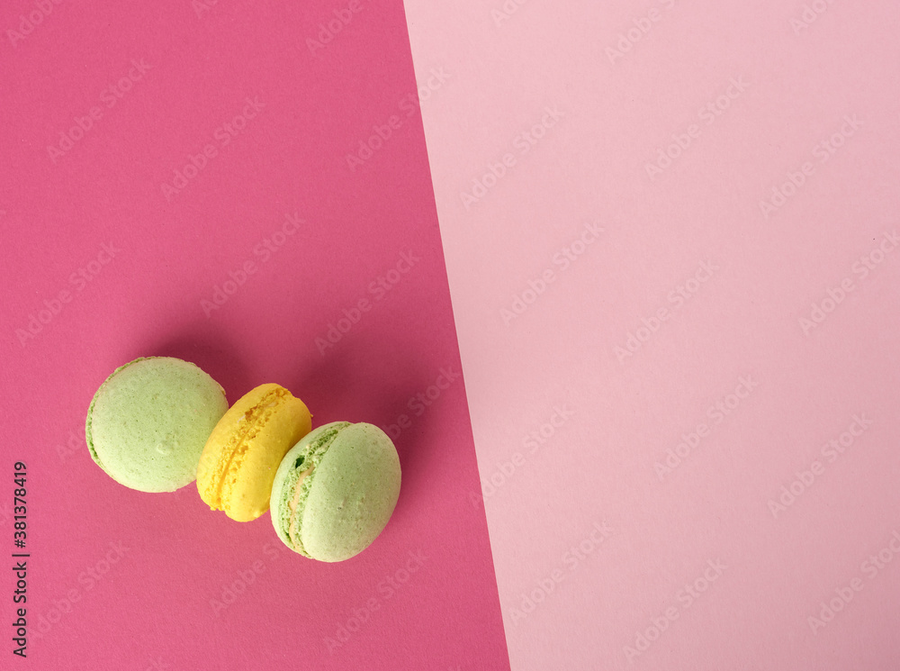 Poster baked multi-colored macaroon cookies lie in a row on a red background