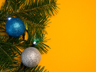 Spruce branches with green needles with garlands and balloons on a yellow background. selective focus