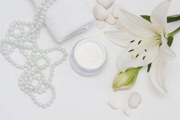Lily (Lilium candidum) face cream with white towel, peals, Lilium fresh flower and sponges, isolated white
