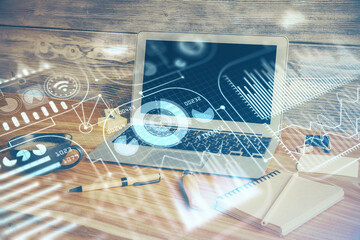 Computer on desktop in office with technology theme hologram. Double exposure. Tech concept.