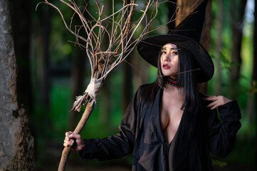 Portrait of beautiful asian sexy woman wear black witch costume with broom,Halloween festival...