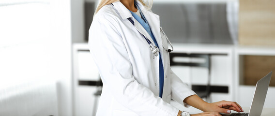 Unknown female physician using laptop computer, close-up. Woman-doctor at work in clinic. Medicine concept