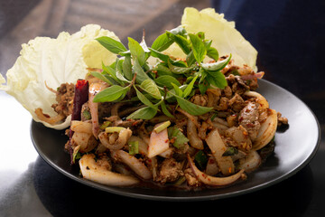 Thai menu spicy minced pork with pork chop into pieces sprinkle with basil. Put on a black plate.