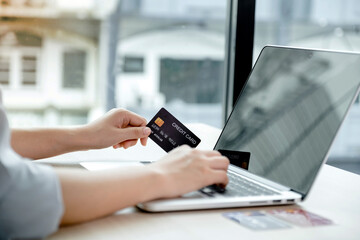 Businessman hand hold credit card to online shopping on laptop computer from home, payment e-commerce, internet banking, spending money for next holidays