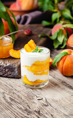 Peach fruit dessert in glass cup on wooden table. Homemade dessert with fruits. Fruit salad with...
