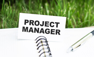 a card with text PROJECT MANAGER on notepad, business concept image with soft focus background