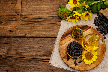 Sunflower oil in glass cruet with flower head and seeds in wooden bowl