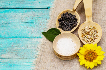Whole and peeled sunflower seeds, sea salt with head flower in wooden spoons