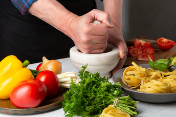 Hands Making sauce for pasta, fresh ingredients on white table