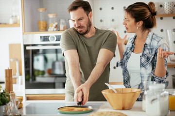 Fototapeta na wymiar Young couple making pancakes at home. Loving couple having fun while cooking.