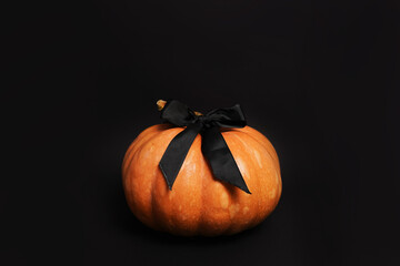 pumpkin with bow on black background. Halloween card concept