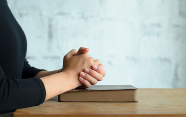 Obraz premium Pray in the Morning, Woman praying with hands together, Woman praying while holding Bible And some of the blurred text in Bible