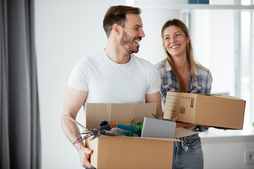 Husband and wife are moving into the apartment. Happy couple is unpacking their belongings