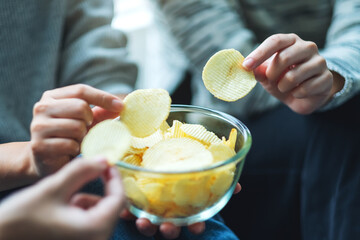 Closeup image of friends sharing and eating potato chips at home party together