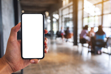 Mockup image of a man holding black mobile phone with blank white screen in cafe
