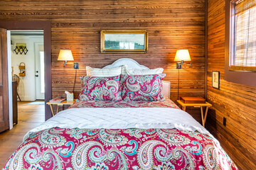 Rustic cabin bedroom with a large bed, quilt and wood-paneled walls and ceiling