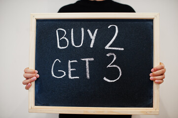 Buy 2 get 3 written on blackboard. Black friday concept. Boy hold board.