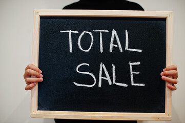 Total sale written on blackboard. Black friday concept. Boy hold board.