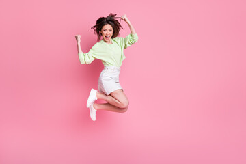 Fototapeta na wymiar Full body profile photo of attractive crazy lady jump up celebrate great win raise fists wear casual green crop pullover naked belly jeans short skirt shoes isolated pink color background