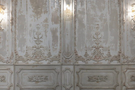 front view of ornate decorative plaster moldings relief wallpaper and white wall crystal lamp in studio