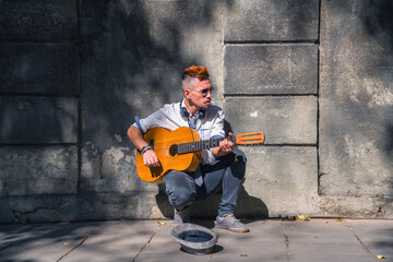 Male street musician playing guitar on the streets of old European city. Horizontal image.
