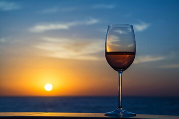 Glass with wine, champagne against  background of  dawn sky and sea