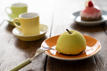 Small French ball shaped cakes mousse dome served on a plate with cups of tea