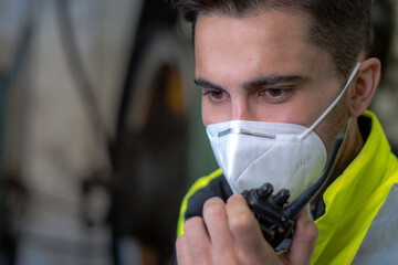 Technical supervisor wearing a mask is operating a crew through a radio communication in the...