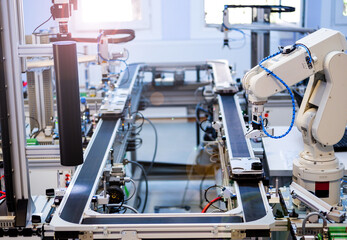 Industry 4.0 concept; artificial intelligence in smart factory prototype. The robot picks up the product from an automated car on the production line. Focus on the robotic arm's gripper.