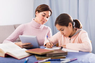 Mother and daughter are doing school homework together at home