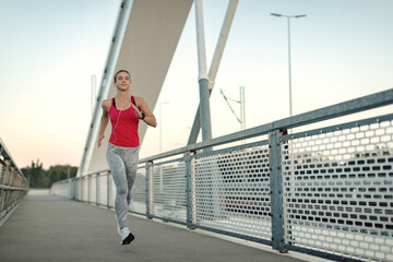 Full length of athletic woman running across the bridge.
