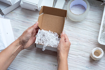 Woman hands holding white paper filler top view in cardboard box