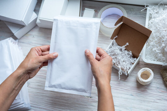 Woman hands holding white paper bubble envelope for postal shipping
