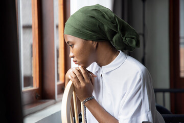 Portrait of sad African young woman cancer patient fighting with the sickness, wearing head scarf...
