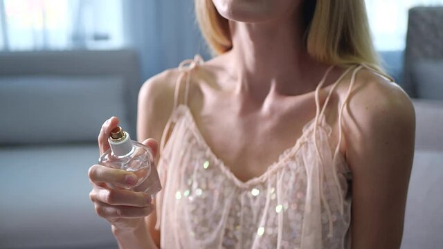Woman spraying on perfume at home, closeup. Slow motion