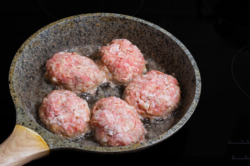 Close up of fried minced meat cutlet in frying pan over black background